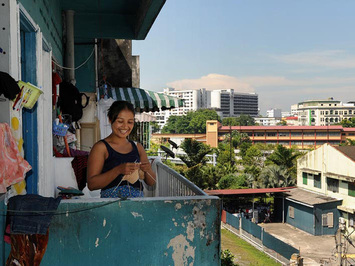 Refugee woman knitting on balcony of her home